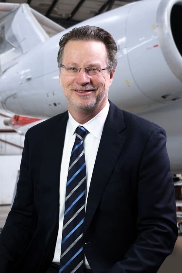 Joel A. English, President, standing in front of a plane